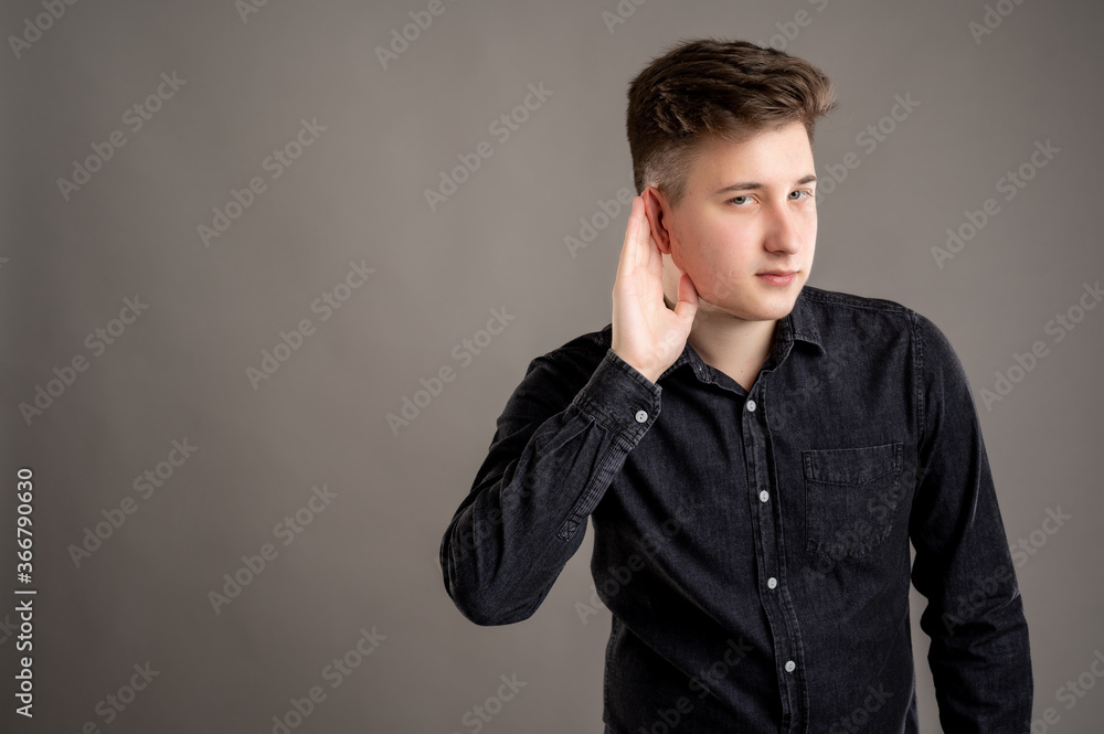 Portrait of serious stylish attractive man dressed in casual black shirt making can't hear you gesture Portrait of serious stylish attractive man dressed in casual black shirt making can't hear you gesture