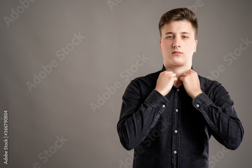 Portrait of serious stylish attractive man dressed with a casual black shirt arranging shirt coller