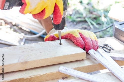 Foto screwdriver. a specialist drives a screw into a wooden surface