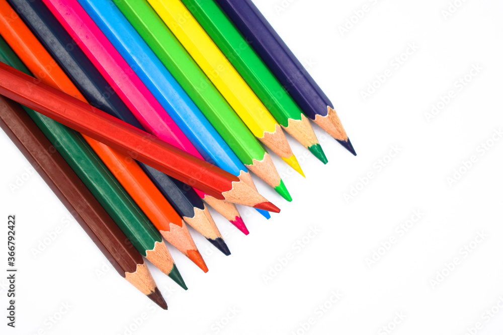 A red color wood pencil crayon placed on top of a row of different color wood pencil A red color wood pencil crayon placed on top of a row of different color wood pencil