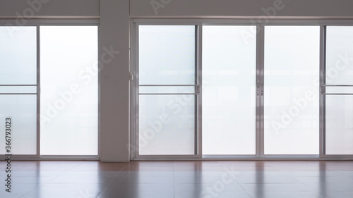 Front view of frosted glass sliding doors with screen doors and light reflection on tile floor surface in empty room 