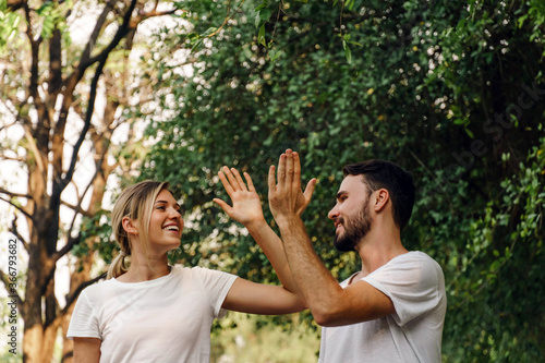 Healthy fit and sportive couple hi five and smile face in nature at summer day. Athletic couple jogging together outdoor.