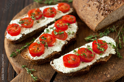 Sandwiches rye bread with cream cheese  and tomatoes cherry on wooden  table