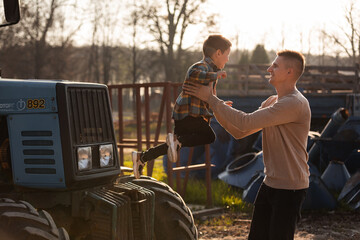 father with his little son having a good time on the farm near the tractors on sunny autumn day. father's day