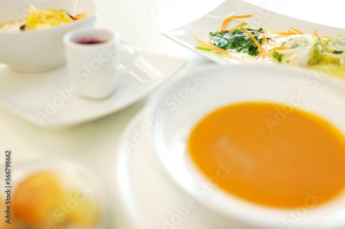 Fine dining food and drink being prepared and displayed in classic white crockery in a kitchen environment,