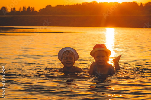 little children splashing merrily in the river in the rays of the setting sun
