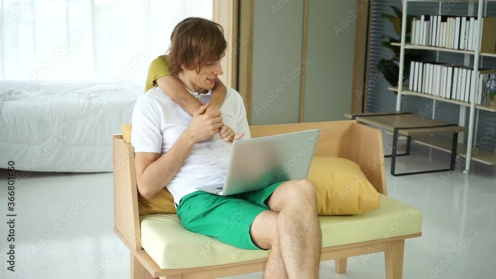 young caucasian white shirt woking on laptop notebook computer with son playing . work from home new normal. young caucasian white shirt woking on laptop notebook computer with son playing . work from home new normal.