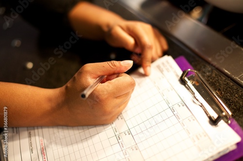 Chef writes down the temperatures of the fridges on the temperature check list,