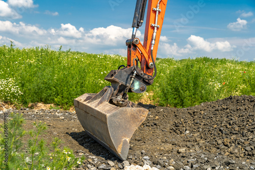 The excavator spreads the ground on the field