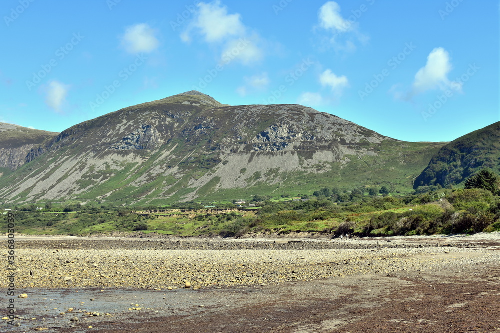 Beautiful, distant mountains at the Welsh seaside.  The shingle  beach at the small seaside village of Trefor on the Llyn Peninsula, north Wales.  A landscape with natural beauty on a summers day.
