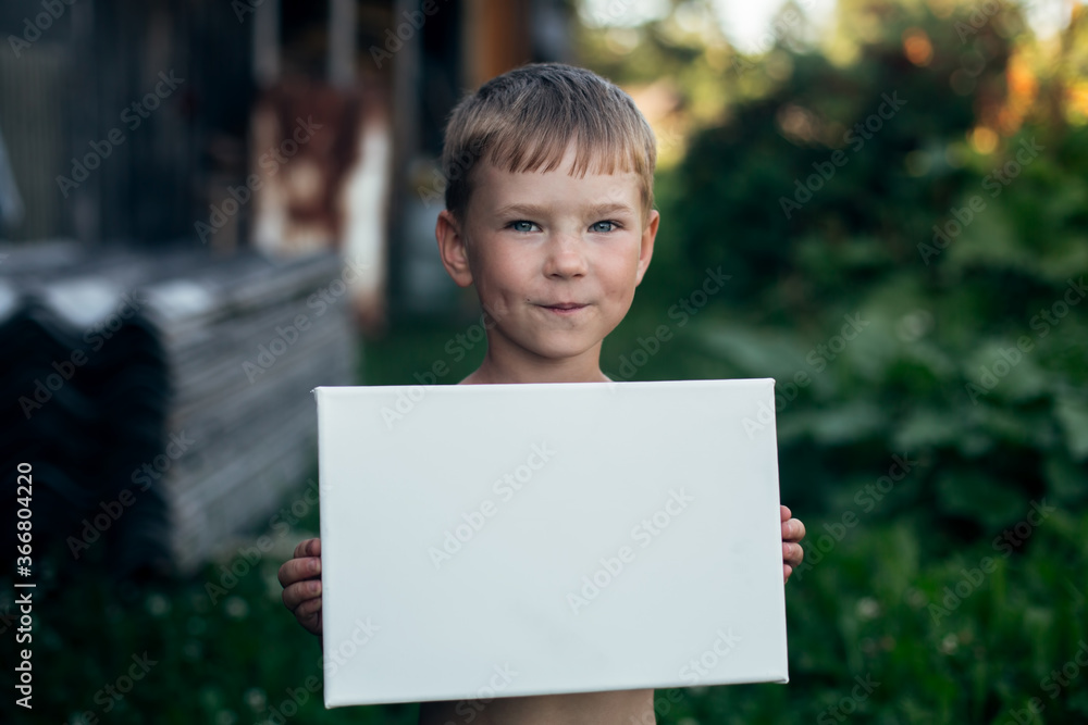 Little boy holding clean white sheet paper (banner for message) Little boy holding clean white sheet paper (banner for message)