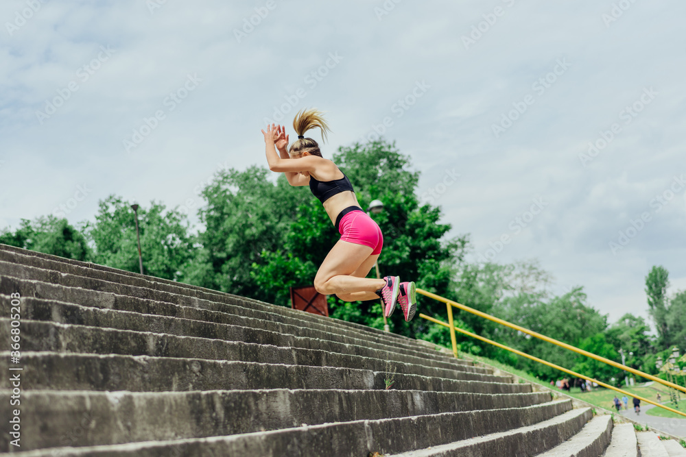 Fit healthy athlete, beautiful woman in tight sportswear jumping on stairs, warming up before jogging while looking highly motivated.. Fit healthy athlete, beautiful woman in tight sportswear jumping on stairs, warming up before jogging while looking highly motivated..