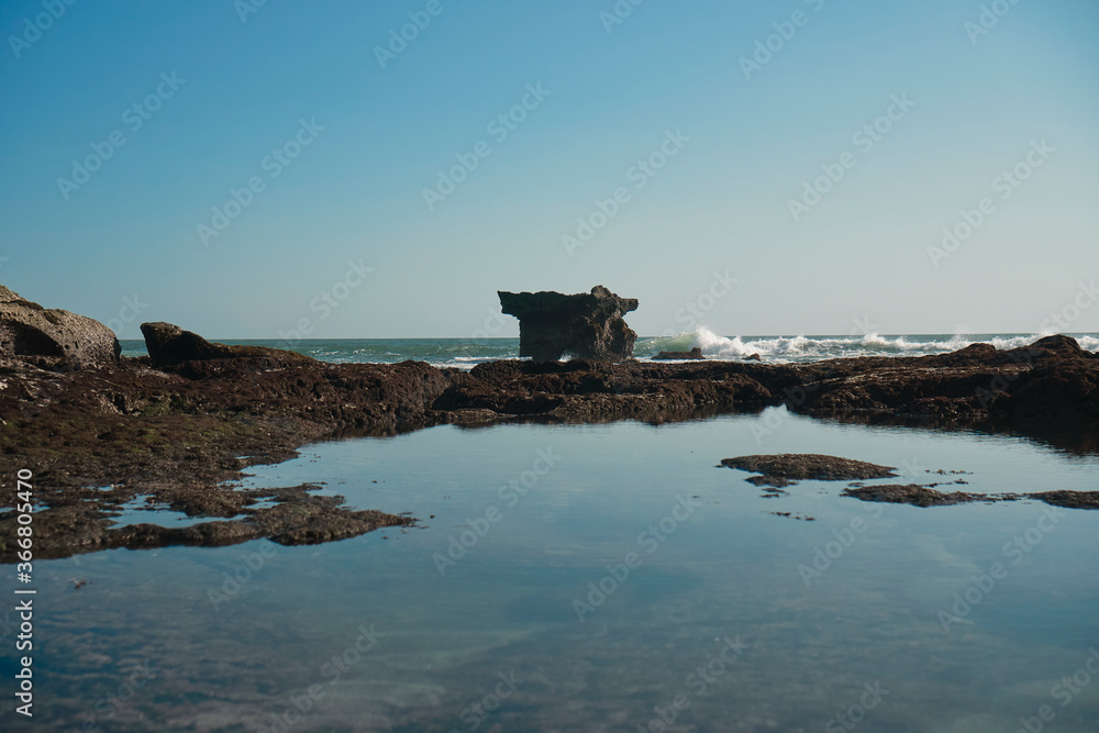 high cliffs in a sea tide of water with a reflection of the sky in the water