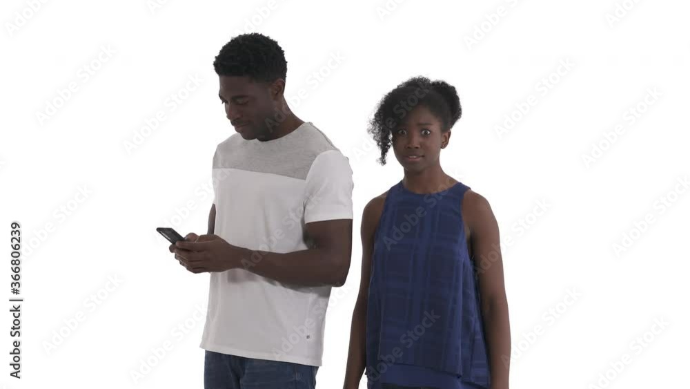 Portrait of curious black girl peeping what typing by mobile phone her African boyfriend isolated on white background Portrait of curious black girl peeping what typing by mobile phone her African boyfriend isolated on white background