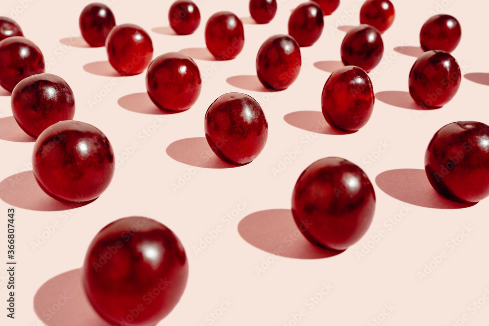 From above pattern of fresh red grapes arranged in lines on pink surface in studio From above pattern of fresh red grapes arranged in lines on pink surface in studio