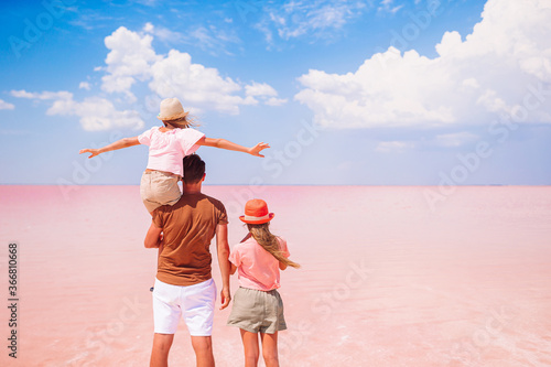 Family walk on a pink salt lake on a sunny summer day.