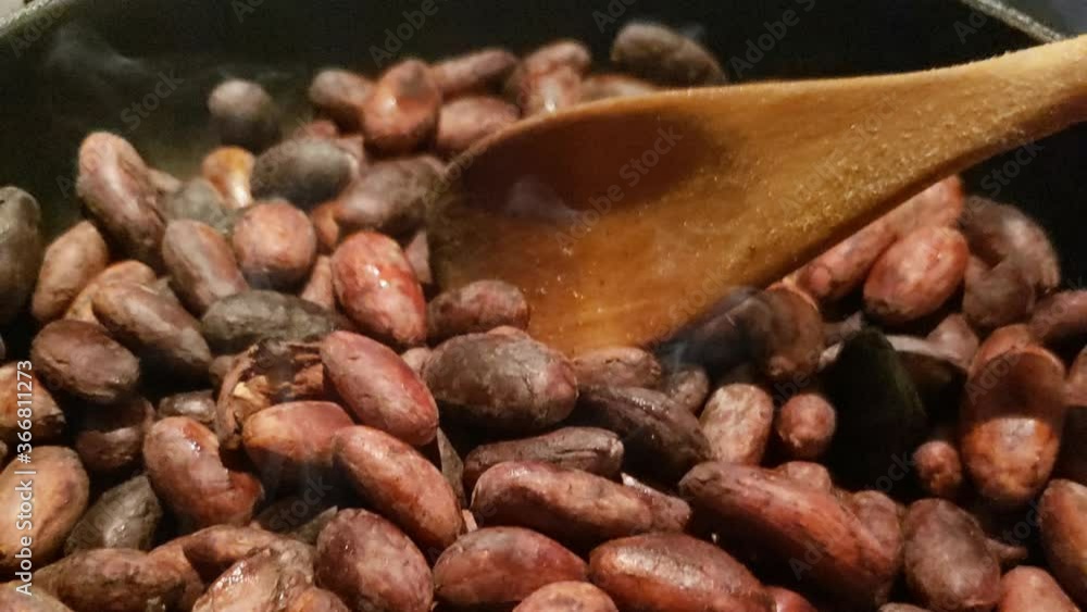 Tostando semillas de cacao con cuchara de palo Tostando semillas de cacao con cuchara de palo