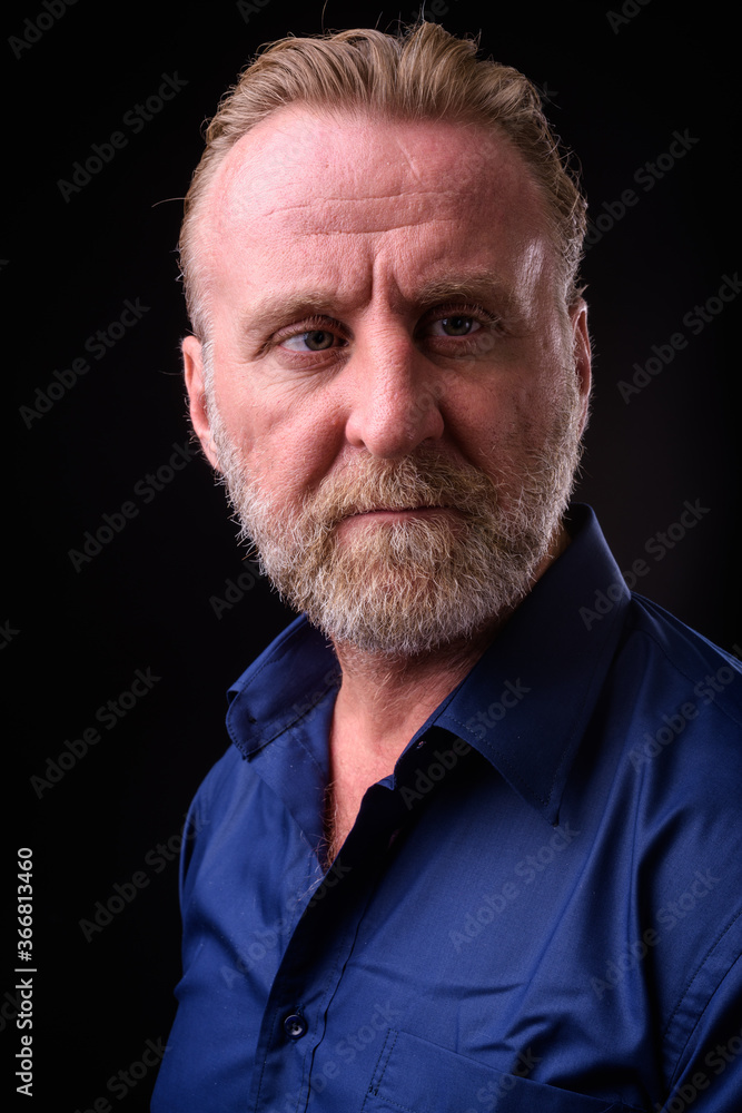 Fototapeta premium Mature handsome bearded man with blond hair against black background
