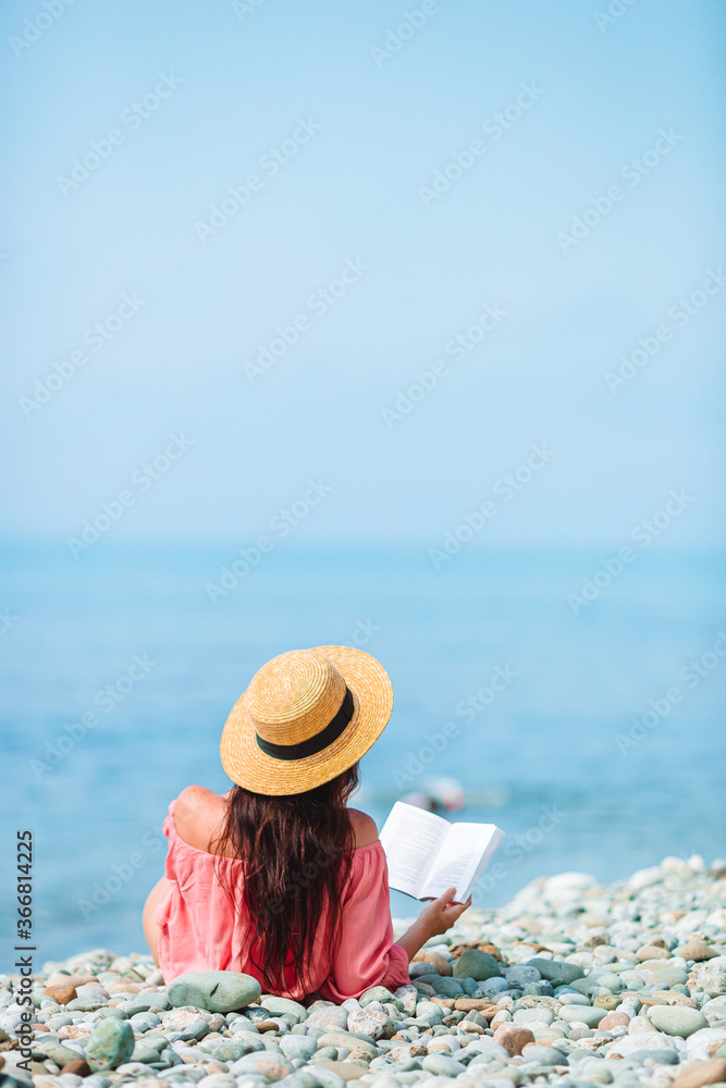Young woman reading book during tropical white beach