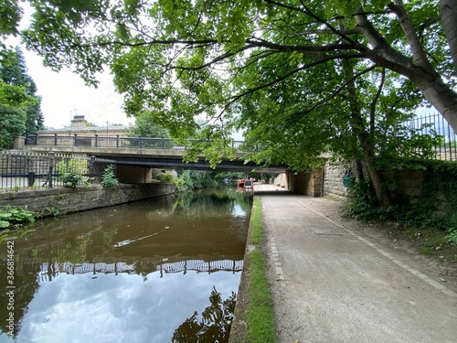 A bridge, crossing over the Leeds to Liverpool canal, with a boat in the distance in, Saltaire, Braford, UK photo