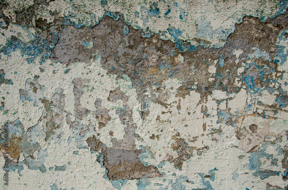 Old flaky plastered concrete wall. Texture of a stone wall with destroyed plaster with blue and light brown shades. Cracks, scrapes, peeling old paint and plaster. Old painted wall background.
