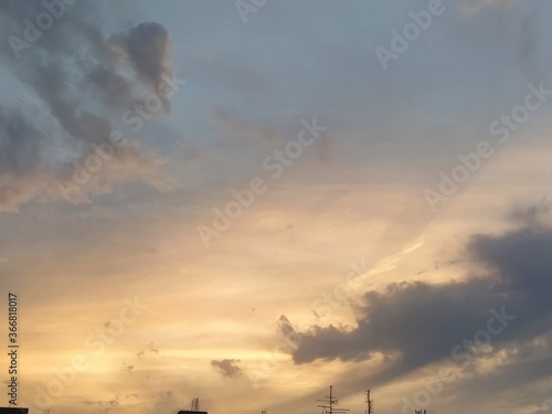 Beautiful dramatic sunset. The sky turned yellow. Dark gray clouds. Clouds lit by the lateral evening sun. Soft warm tones and colors. Summertime atmosphere. photo