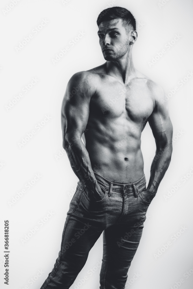 Fototapeta premium Male shirtless model with perfect body in jeans posing over white background. Close-up. Studio shot.
