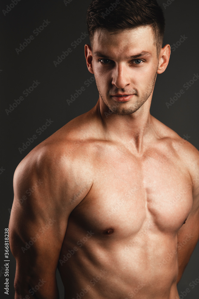 Male beauty concept. Portrait of handsome mucscle young man posing over gray background. Perfect hair & skin. Close up. Studio shot