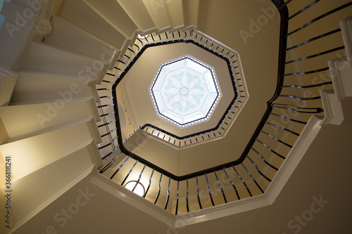 View from the bottom of a spiral staircase looking up to the centre point in the roof of an art deco window,
