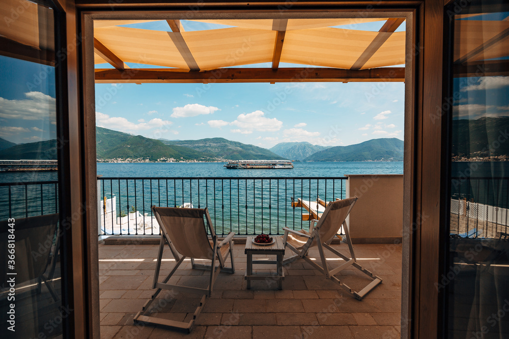 Two sun loungers on the balcony of the hotel room overlooking the sea and a passing tourist boat.