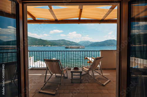 Canvas Print Two sun loungers on the balcony of the hotel room overlooking the sea and a passing tourist boat