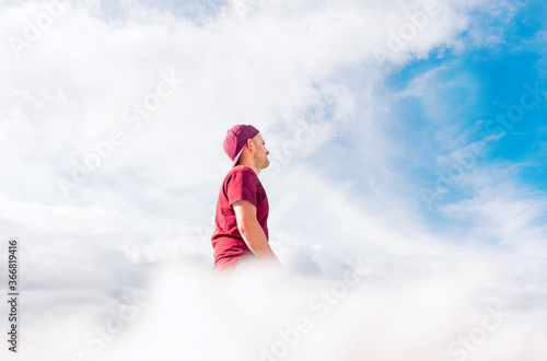 Young man is sitting on the clouds while thinking and imagining