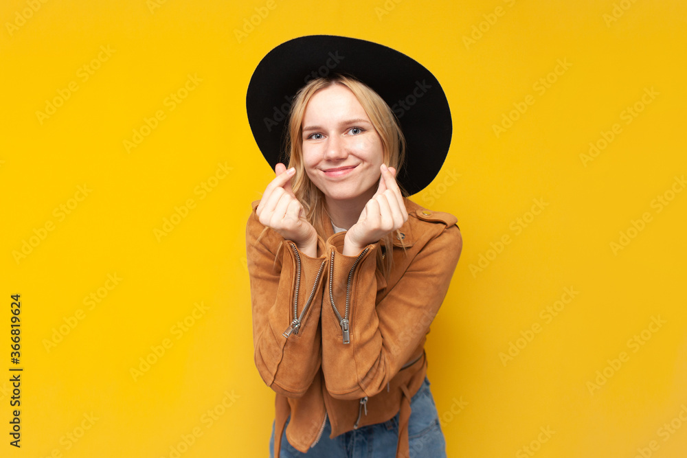 girl in autumn clothes shows a heart with her hands and smiles on a yellow isolated background girl in autumn clothes shows a heart with her hands and smiles on a yellow isolated background