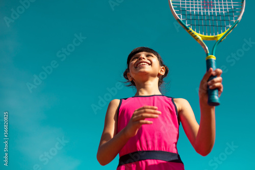 smiling girl playing tennis under blue sky © kevin