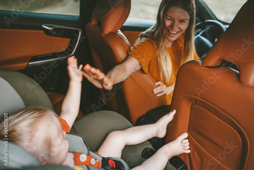 Quadro su tela Mother with child in car on road trip high five hands baby sitting in safety sea