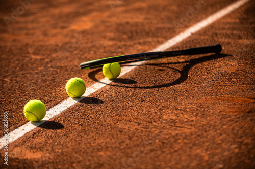 three tennis balls lined up on a white line of a clay tennis court © kevin