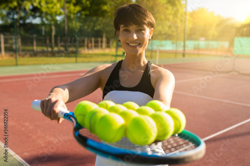 woman's hand showing tennis racket with tennis balls