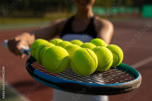 woman's hand showing tennis racket with tennis balls