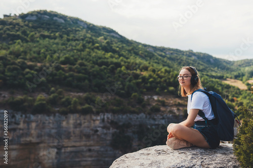 tourist woman with backpack listens music with headphones enjoy freedom of  hiking background panorama mountain landscape on vacation outdoors empty space