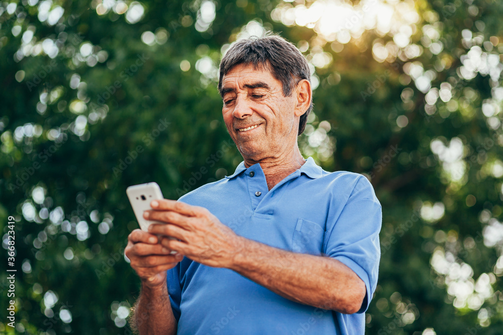Man in his seventies using smartphone outdoors Man in his seventies using smartphone outdoors