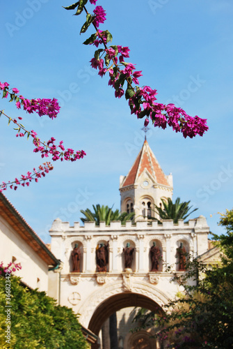 basilica entrance with portico with statues and flowers in the foreground photo