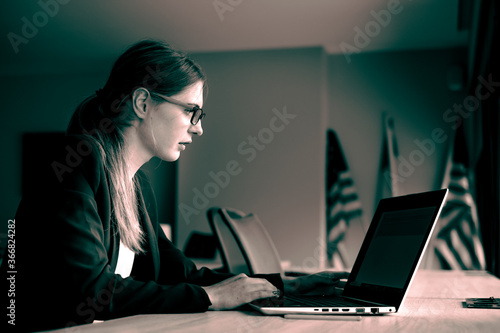 Business girl in glasses with a laptop sitting in front of the window. Development of women's business