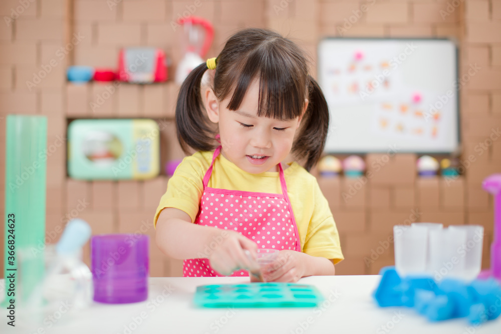 toddler girl making sweet gems for homeschooling in the kitchen build by cardboard toddler girl making sweet gems for homeschooling in the kitchen build by cardboard