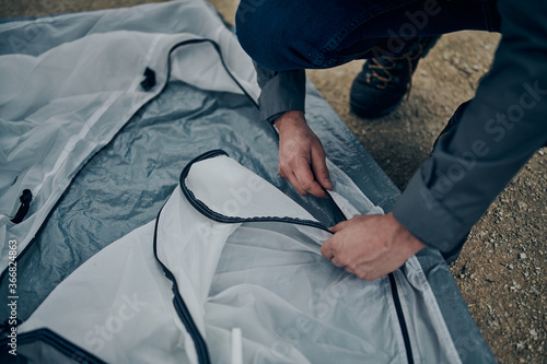 Closeup of men adjusting tent on camping trip.