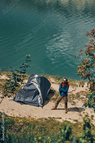 Man standing next to tent on camping trip and admiring beautiful nature.