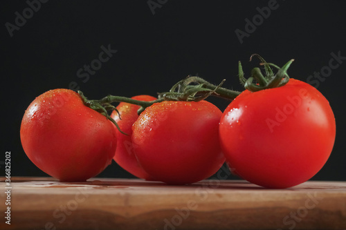 Fresh tomato with water drops on a wooden board, Black background.