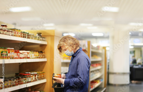 Supermarket shopping, face mask and gloves,Young man shopping in supermarket, reading product information