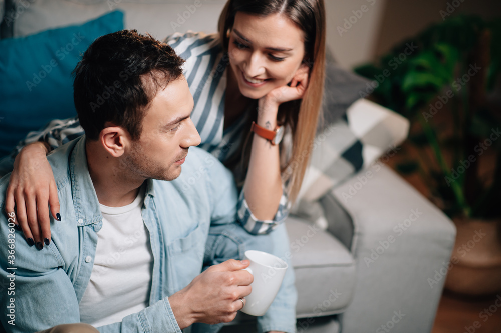 Portrait of a young couple in casual clothes on the couch in hugging each other Portrait of a young couple in casual clothes on the couch in hugging each other