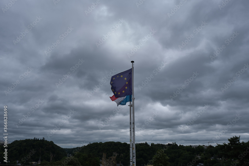 European and Luxembourg flag at a cloudy day in summer European and Luxembourg flag at a cloudy day in summer