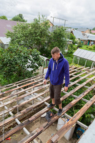 Young man Dismantling Old corrugated polycarbonate roof on the village house